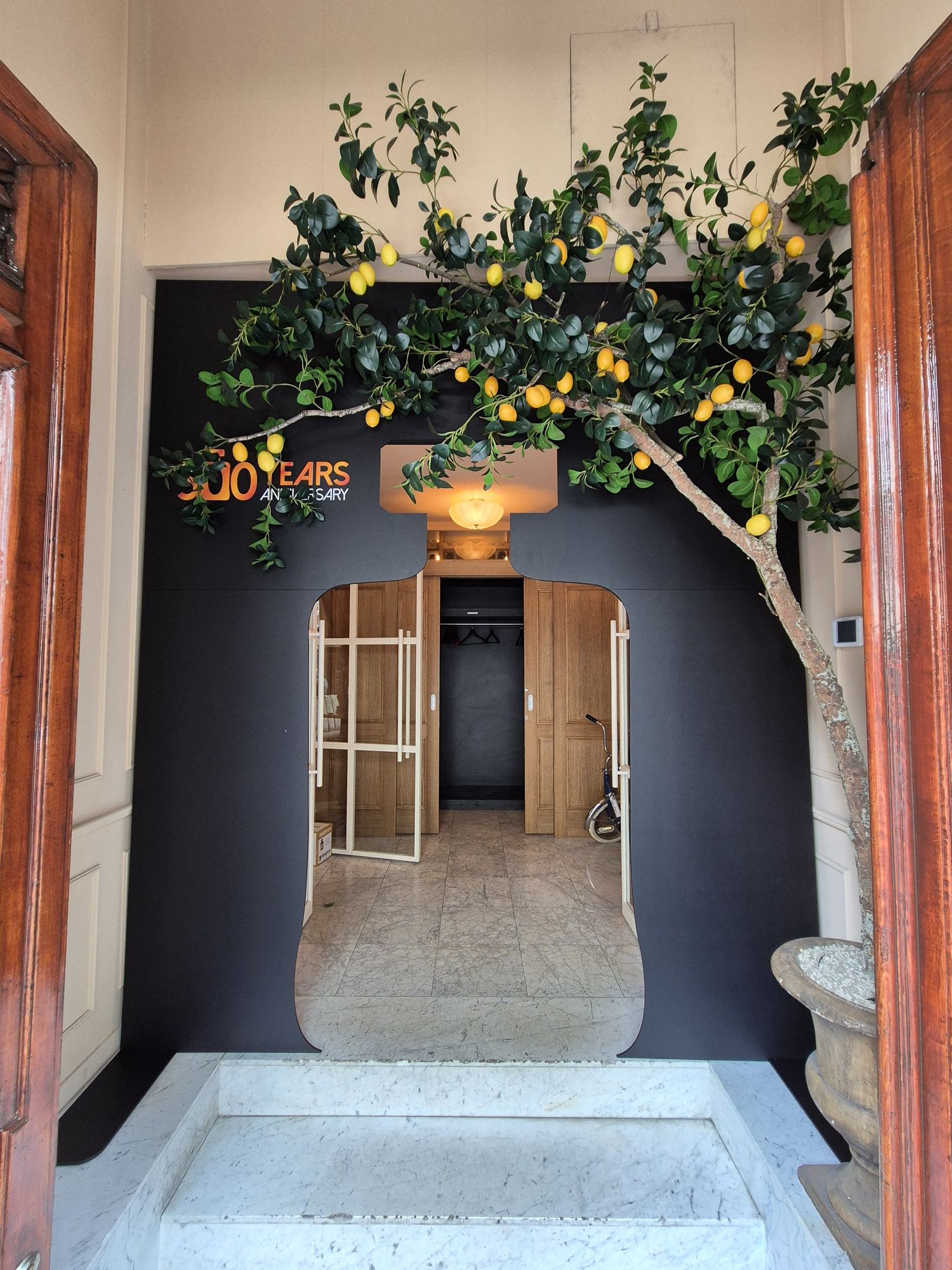 Front view of the black bottle-shaped entrance beneath a lemon tree
