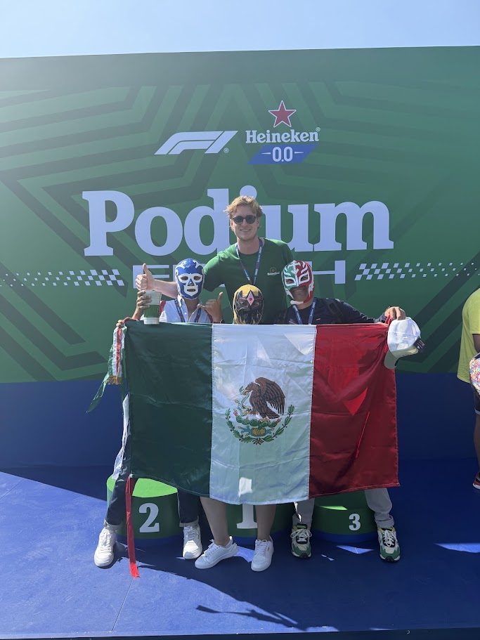 Mexico Grand Prix visitors posing behind the podium with a large Mexican flag