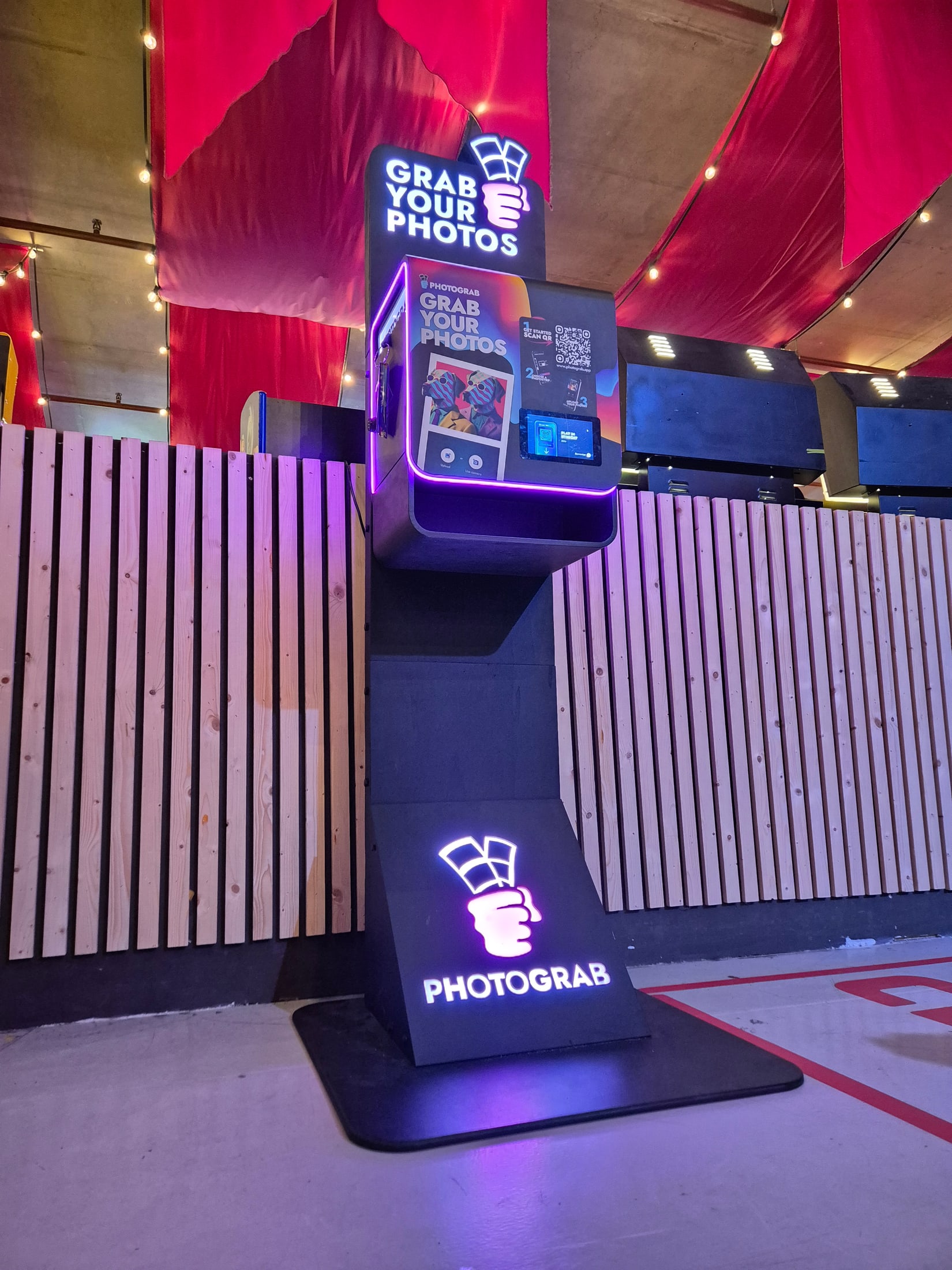 Tall illuminated PHOTOGRAB station at an evening event